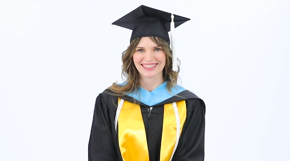 A female smiling at the camera wearing graduate student graduation regalia