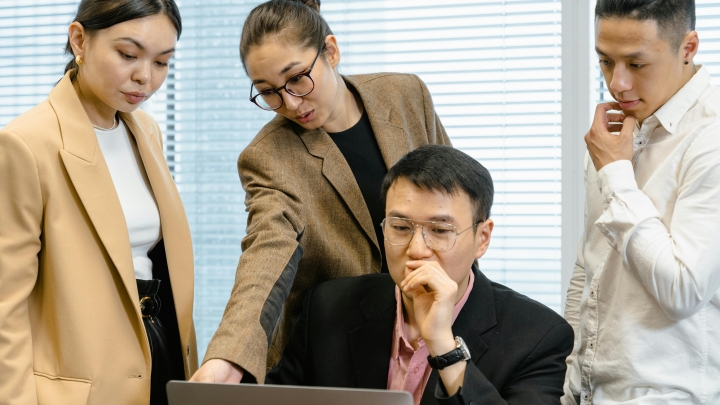 Four colleagues working together around a computer