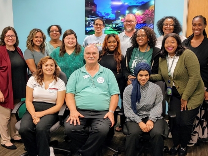 14 members of counseling center staff pose for picture in front of room decorated with crepe paper.