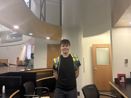 Viking Safety Ambassador wearing green vest and standing behind the student center PD Hub desk