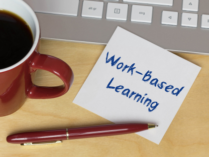 Cup of coffee by a computer keyboard with a note stating work-based learning